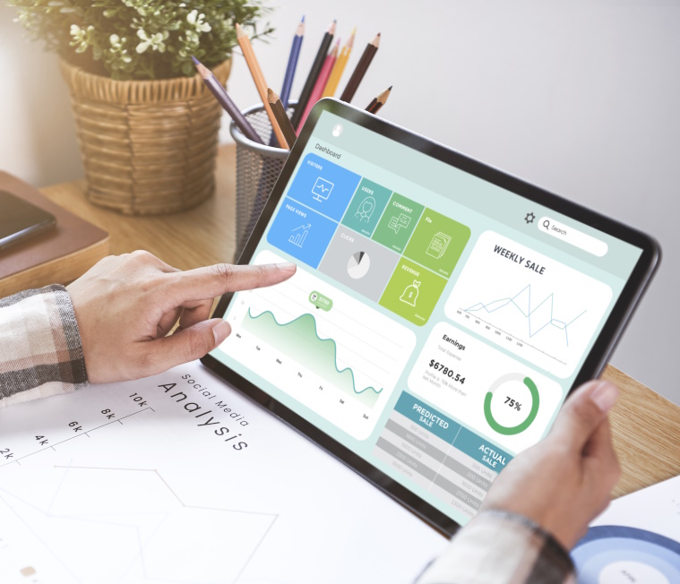 Photo of a man holding a tablet and pointing to a dashboard UI.